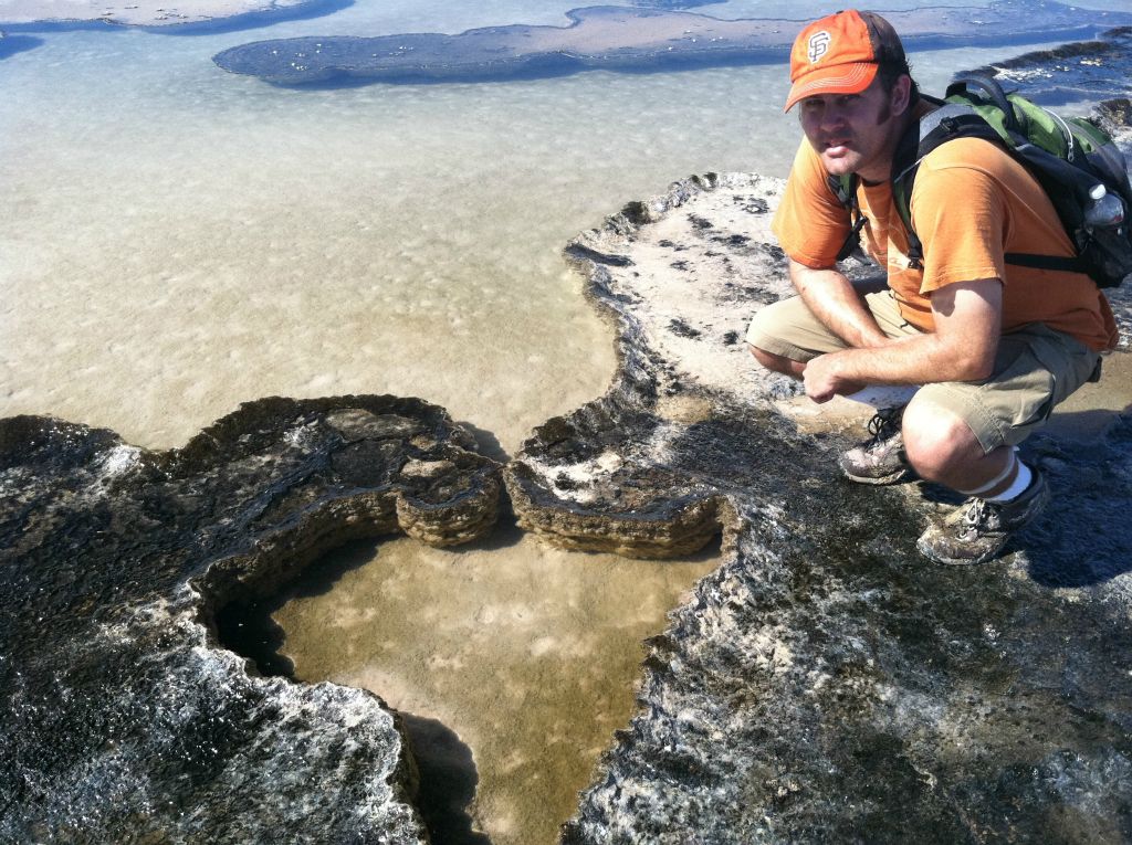 Very carefully getting a picture next to a heart-shaped pupfish pool.  Notice that my hiking boots have taken a beating and been consumed by muck: